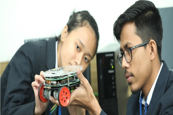 Students examining a robotic device